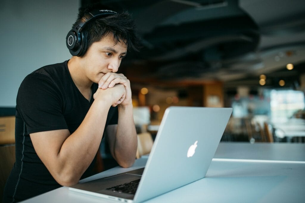 woocommerce vs magento man wearing headphones while sitting on chair in front of MacBook