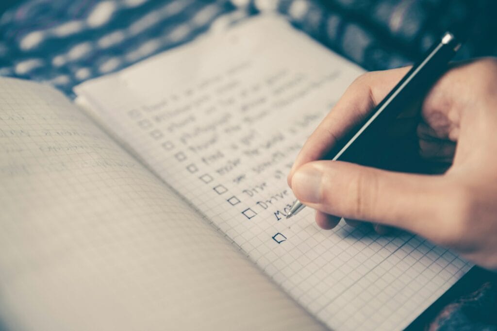 woocommerce vs magento person writing bucket list on book