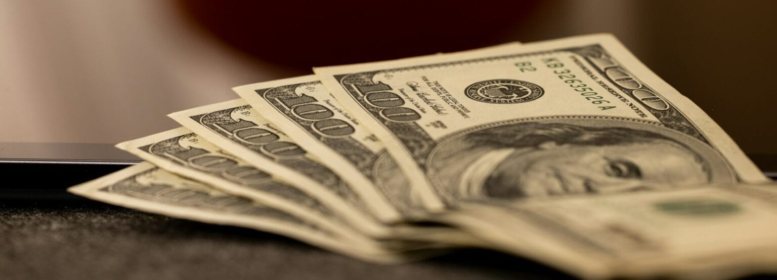woocommerce vs magento a stack of money sitting on top of a laptop computer